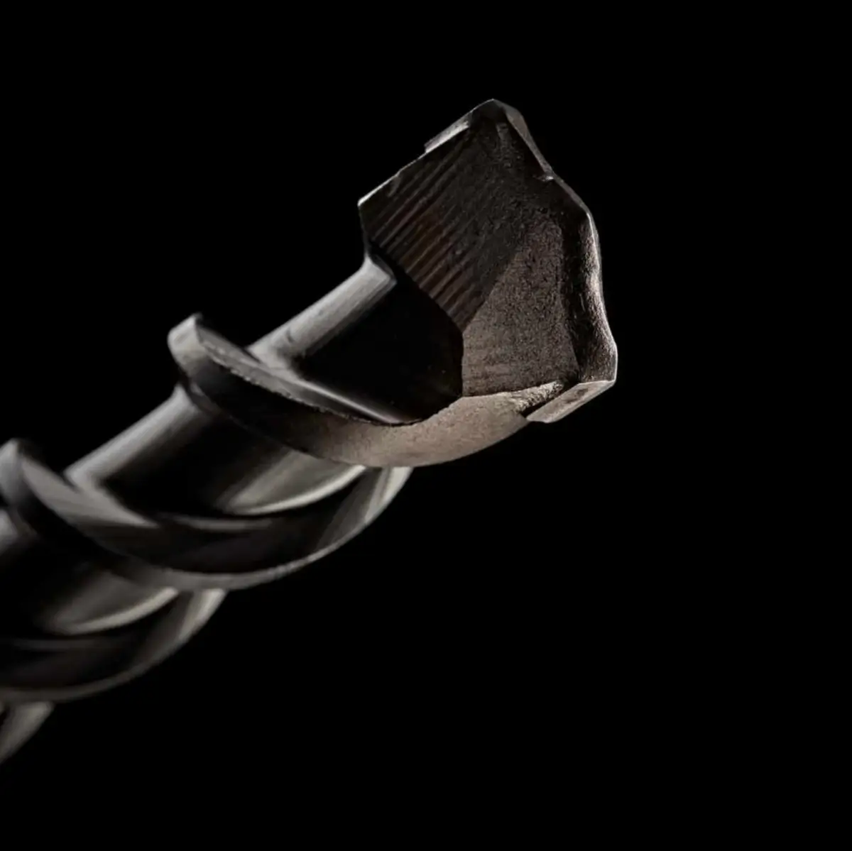 Close up of cross tip hammer drill bit against black background
